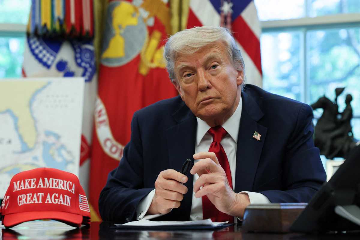 Trump at desk with MAGA hat