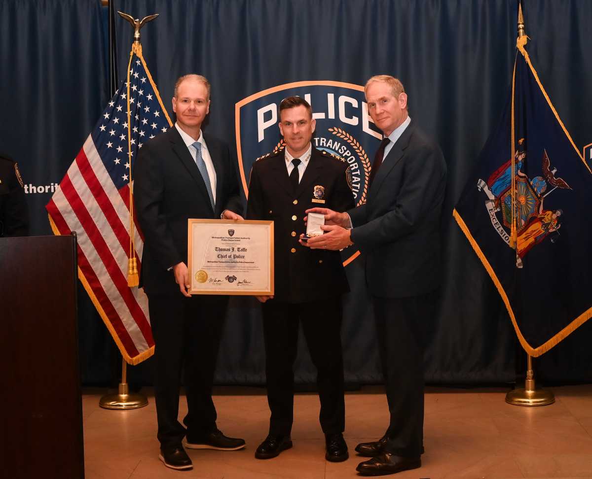 three men on a stage with American flag behind them