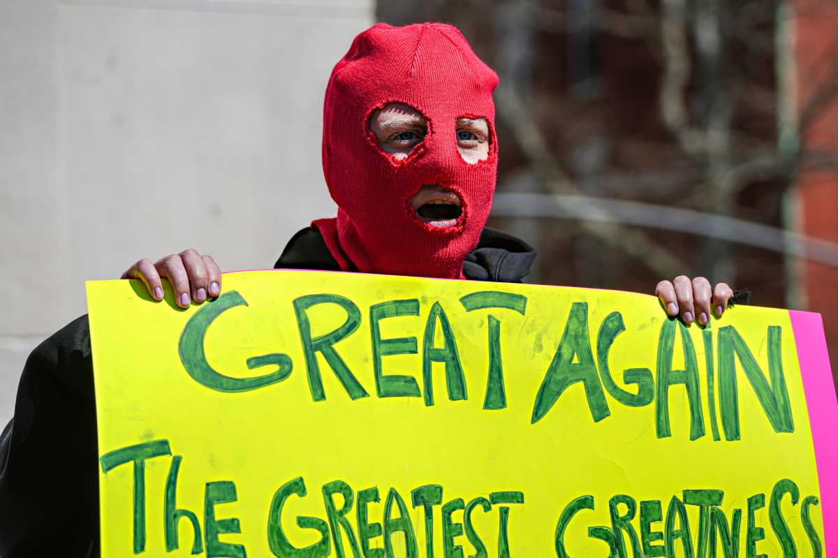 Pussy Riot member in mask holding up sign against authoritarianism