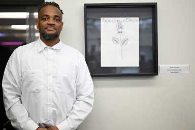 Brian Croskey poses alongside his artwork 'Black Flower.' He recreated the piece, dedicated to his sister, during a Black History event on Rikers this year. The original proudly hangs in his sister's home.