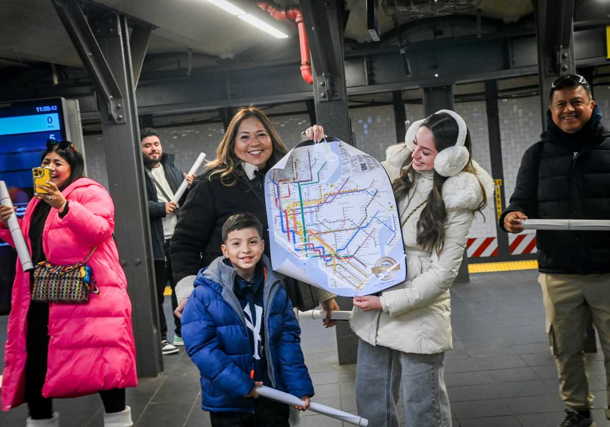 people in a train station holding new subway map