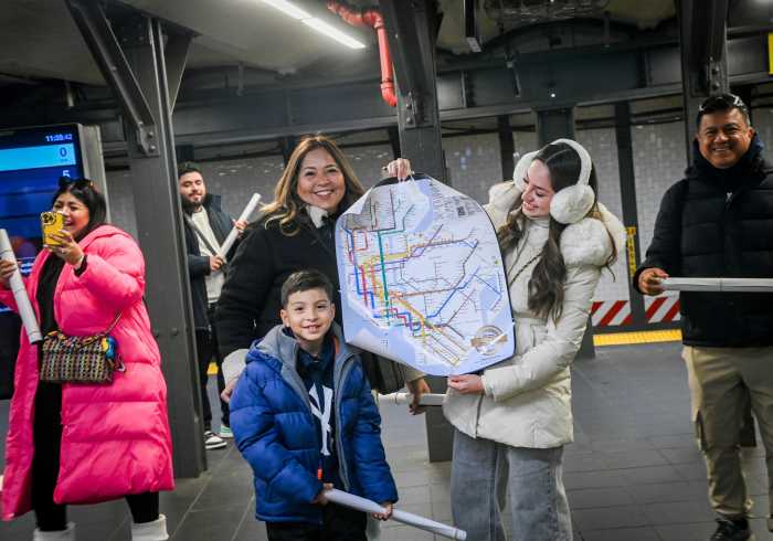 people in a train station holding new subway map