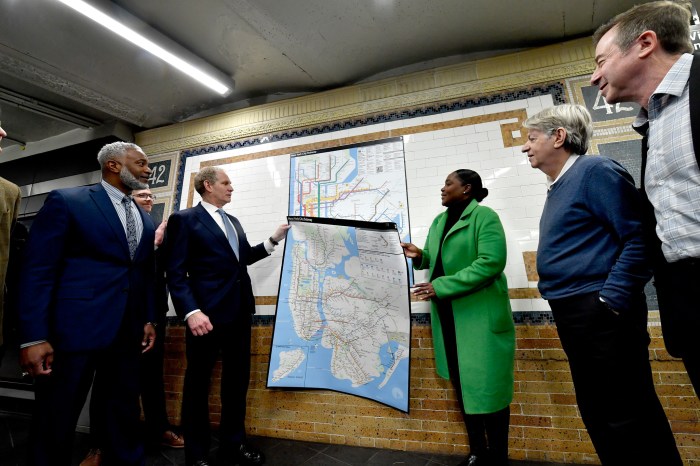 people holding. a map of NYC inside a subway station