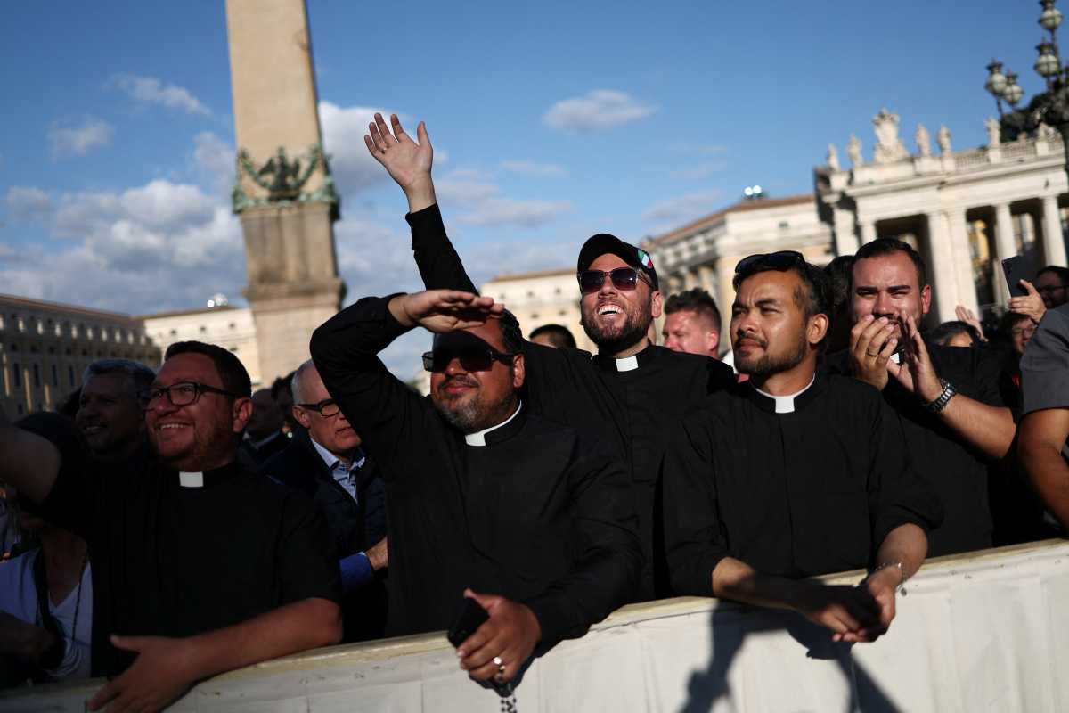 Priests react to white smoke marking election of pope in St. Peter's Square in Rome