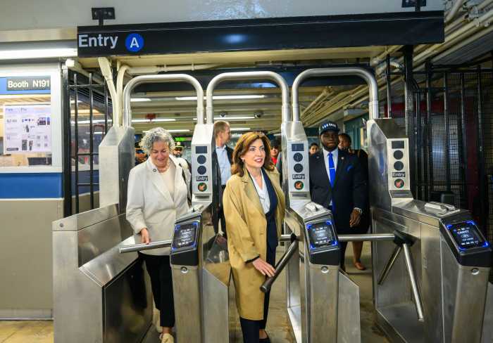 people walking through a subway turnstile