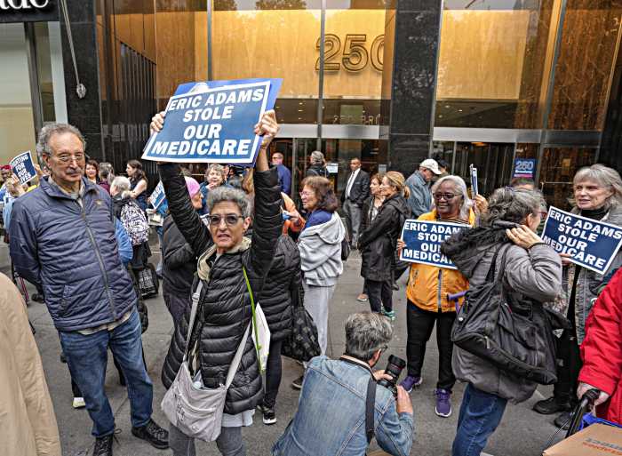 retired NYC workers hold signs demanding protection of their healthcare plans