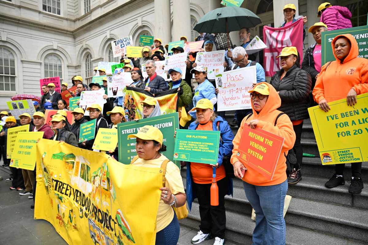 Street vendors gather at City Hall holding signs seeking street vending reform