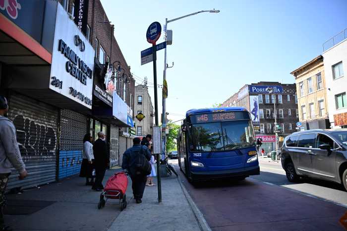 a NYC bus approaches a bus stop
