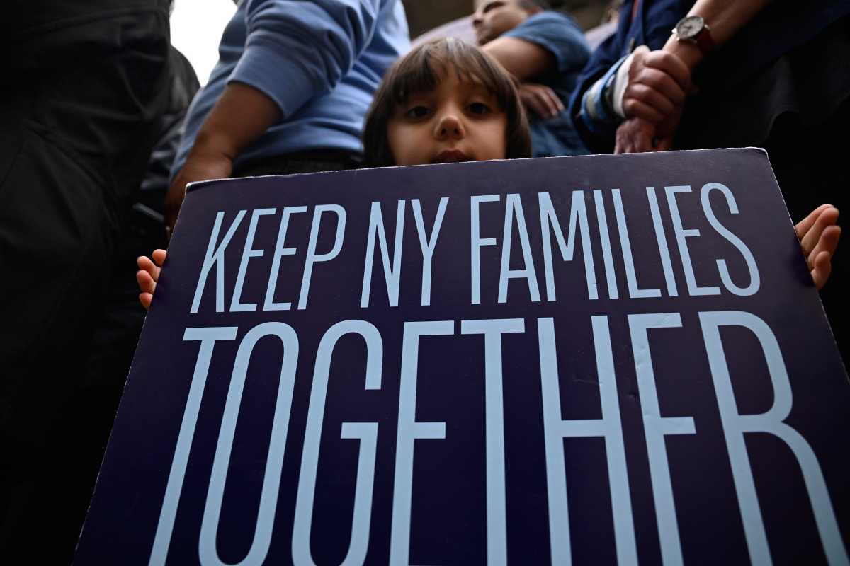 a child holds a sign that says "Keep NY Families Together"