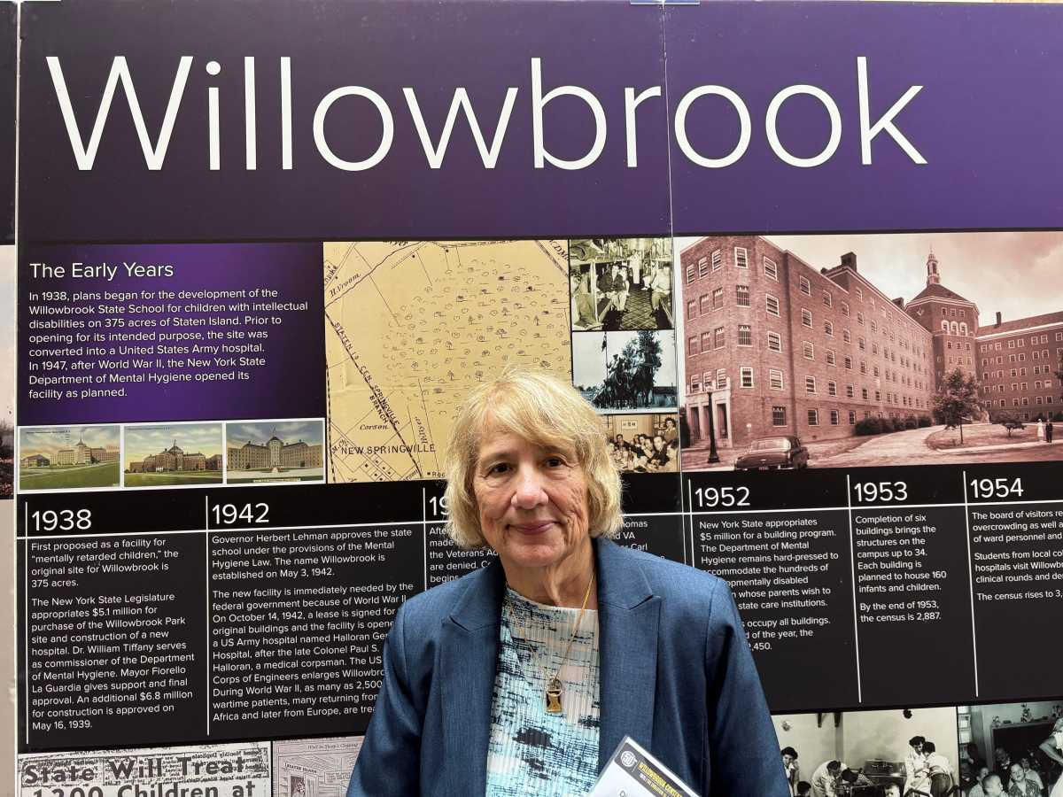 woman standing in front of exhibit marking history of Willowbrook State School