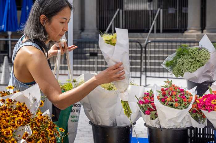 Union Square, Manhattan, New York, USA - August 11th 2023: Asian woman looking at bouquets at a flower stall at a farmers market