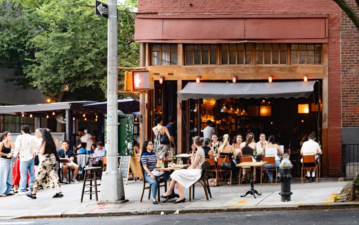 On a summer day many people sit and dine outdoors at a sidewalk cafe in Soho, NYC. NYC dining concept