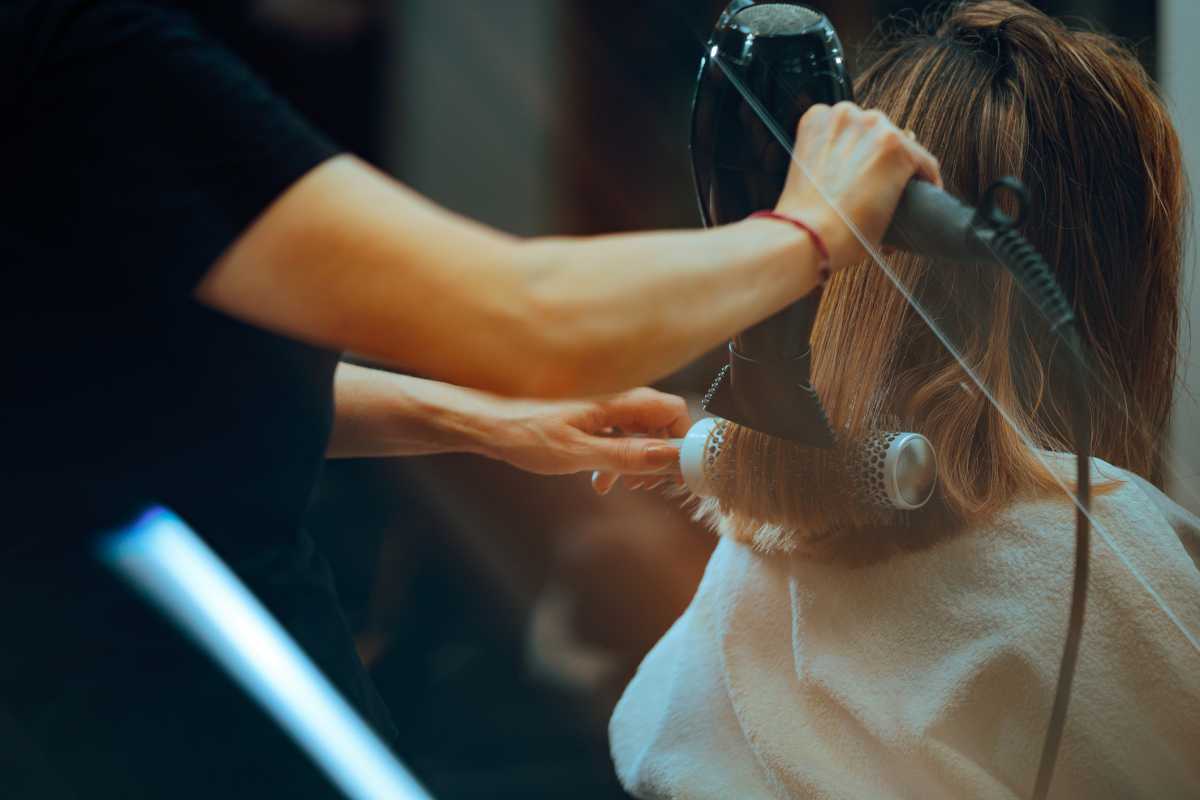 Hairdresser drying clients hair working with professional tools