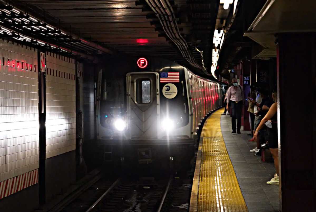 F train pulling into a station in Queens