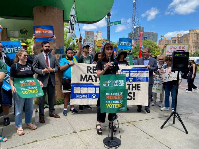 woman speaking at a podium during a rally for better bus service in Brooklyn