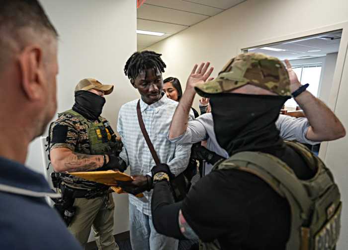 man looking at federal ICE agents wearing masks and body armor