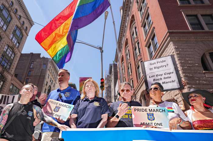 Police commissioner and groups of plain-clothed officers under pride flag