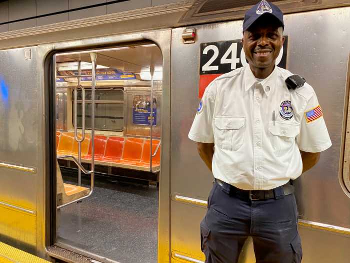 man in a white shirt standing outside a subway train