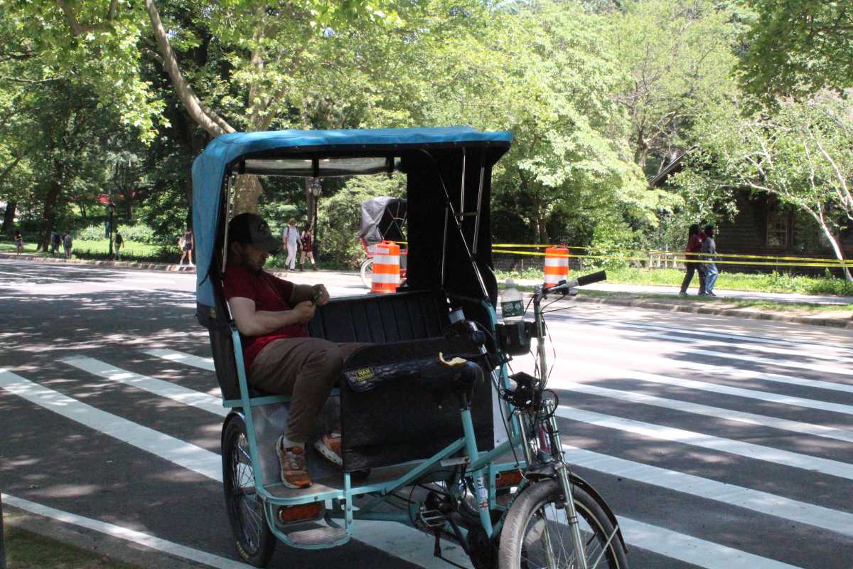 a man seeks shade in a peddycab in new york city during a heat wave