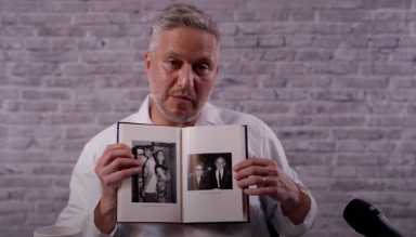 Immigrant man holding up book of family photos