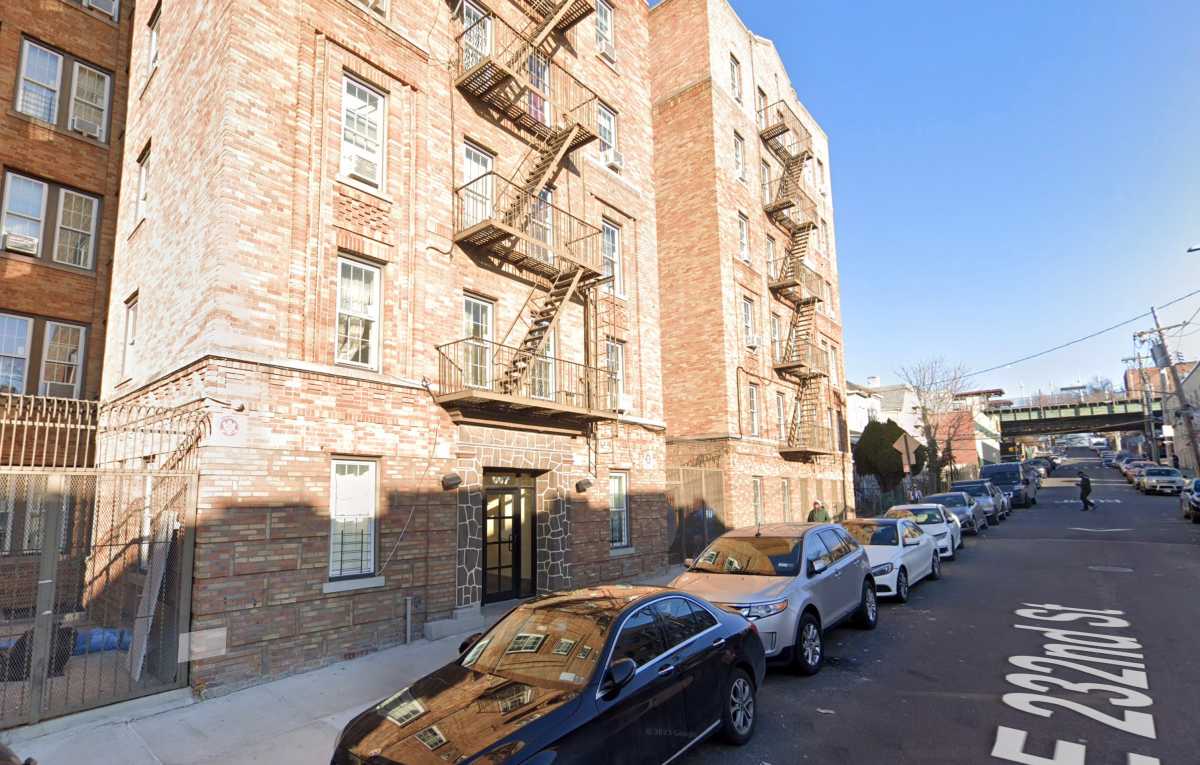 apartment building with sun beaming down and cars parked inf ront