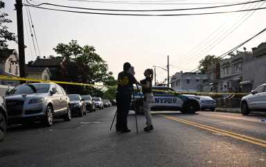 Two officers at crime scene with camera taking images in front of police car