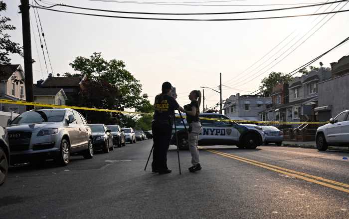Two officers at crime scene with camera taking images in front of police car