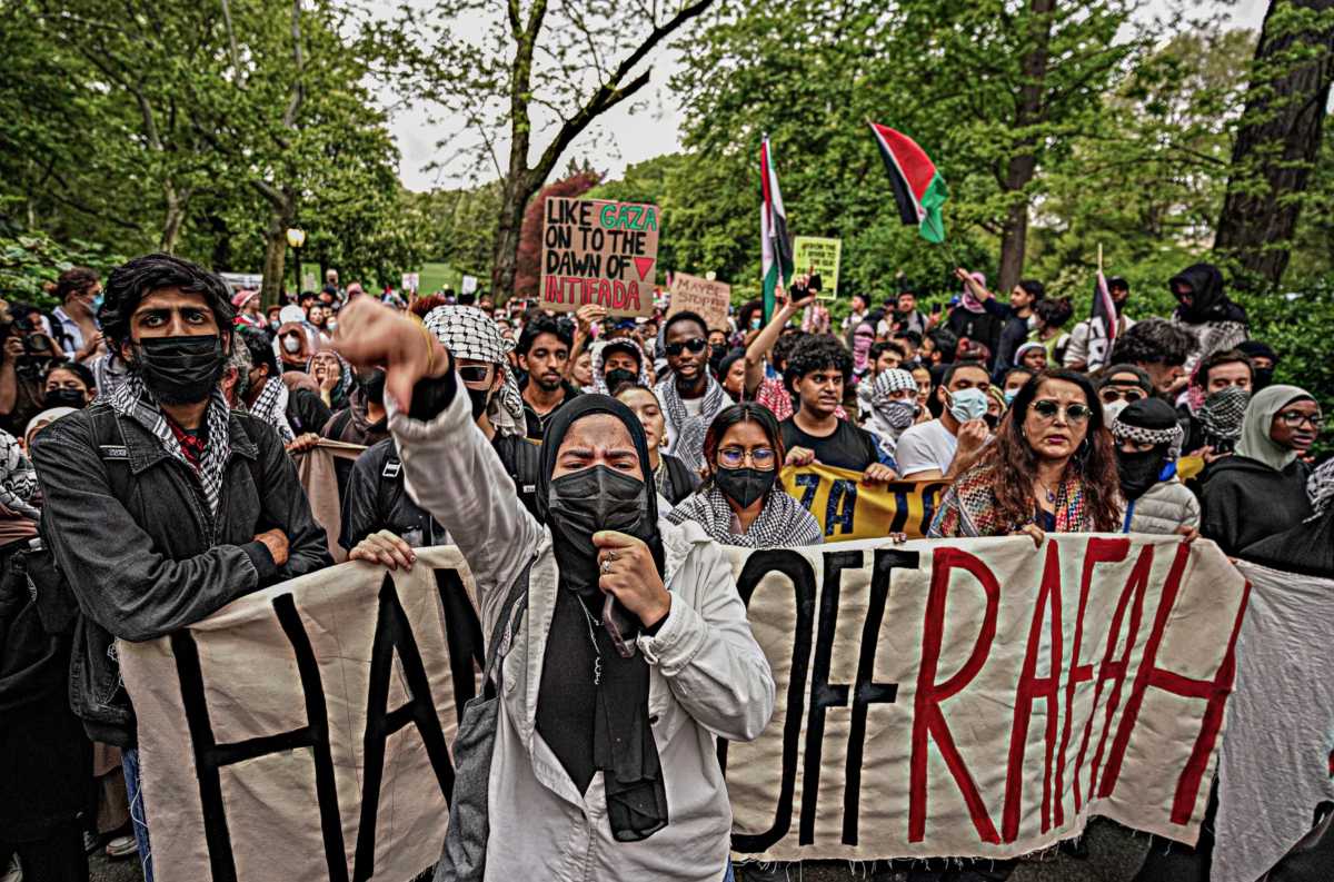 Pro-Palestine demonstrators carry signs against war and mentioning intifada