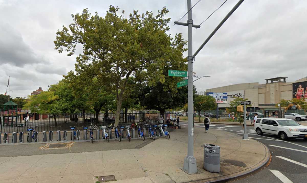 street scape with tree, sign  and large sidewalk with traffic going by