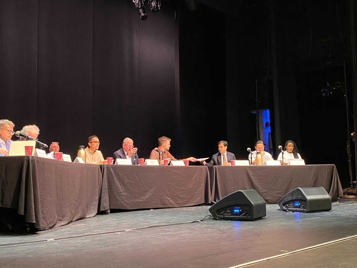People sitting at table with black drapes voting on rent increase