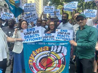 people gathered around a sign advocated for Uber and Lift drivers