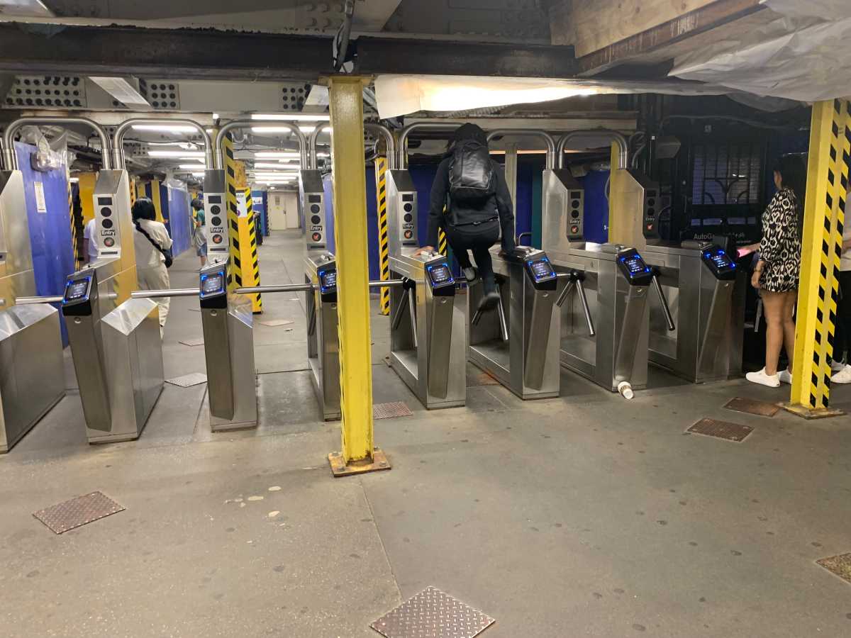 person jumping over a NYC subway station turnstile