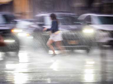Person running into rain-soaked street in New York City amid flooding rain