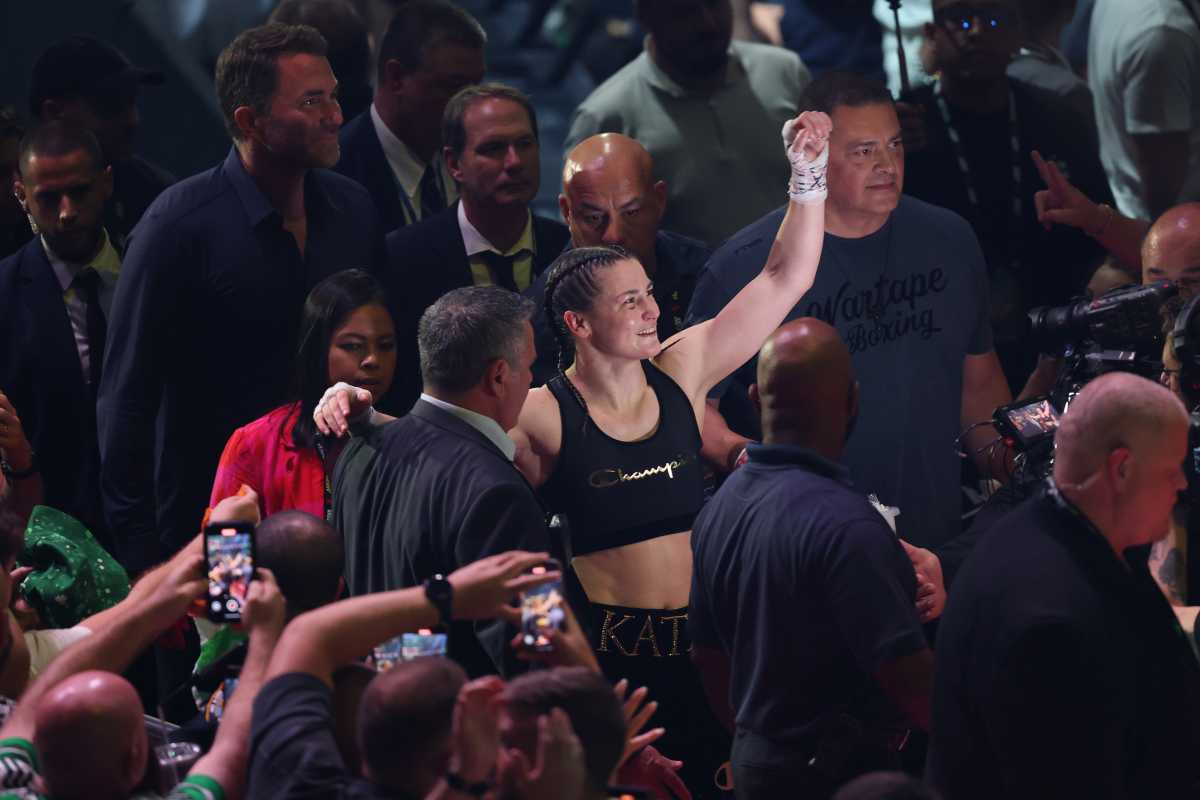 woman boxer in tank top raises fist to crowd after winning match