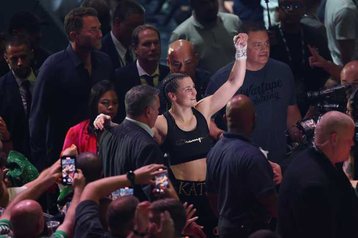 woman boxer in tank top raises fist to crowd after winning match