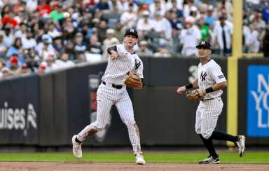 Yankees player in white pinstripes throws the ball