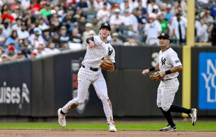 Yankees player in white pinstripes throws the ball