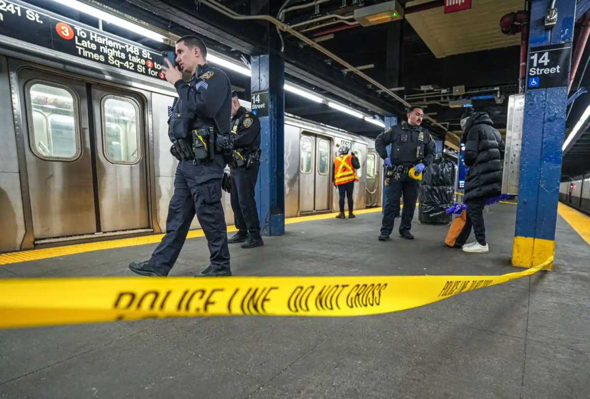 nypd officers in blue on subway platform with yellow crime scene tape stretched