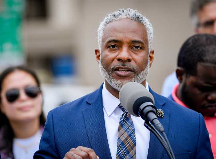 Man with gray hair and beard speaking into microphone.