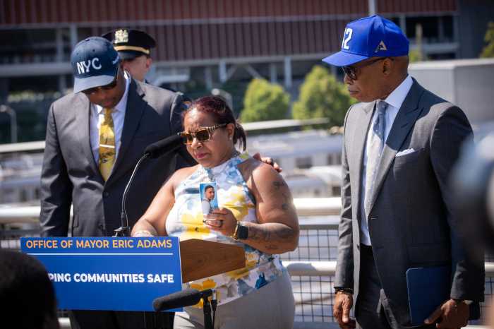 Norma Nazario holds up a funeral card for her 15-year-old son, Zachary, who died while subway surfing in 2023, during a press conference with city officials in Queens on Monday