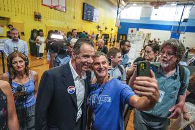 people smiling at campaign event as candidate Cuomo poses for photo with woman
