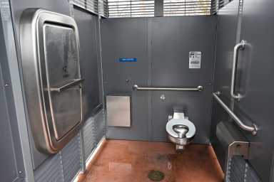 Inside the Irving Square restroom in Brooklyn. The stainless-steel bathroom includes a toilet, hand sanitizer, baby changing station, and slatted openings for ventilation and safety.