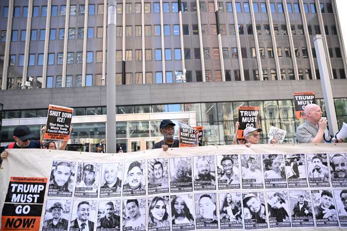 Protesters hold a banner displaying images of detained immigrants outside 26 Federal Plaza during a rally against ICE detentions.