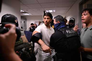 ICE agents escort a man through the hallway of 26 Federal Plaza following a court hearing.