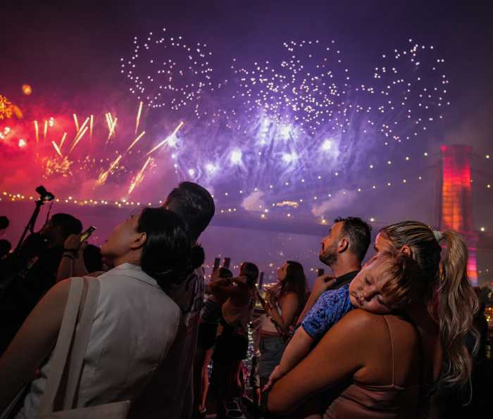 Young child sleeping on mom's arm while other people watch the Macy's Fourth of July Fireworks Extravaganza