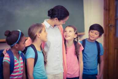 Teacher and pupils smiling in classroom at the elementary school