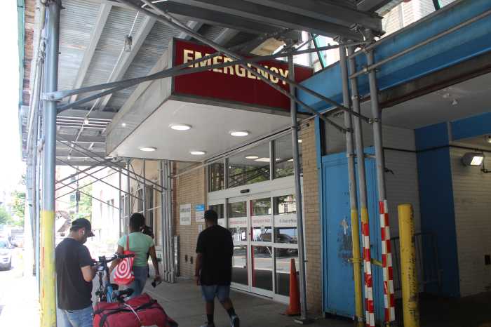 emergency room entrance at a hospital in Harlem with people walking by