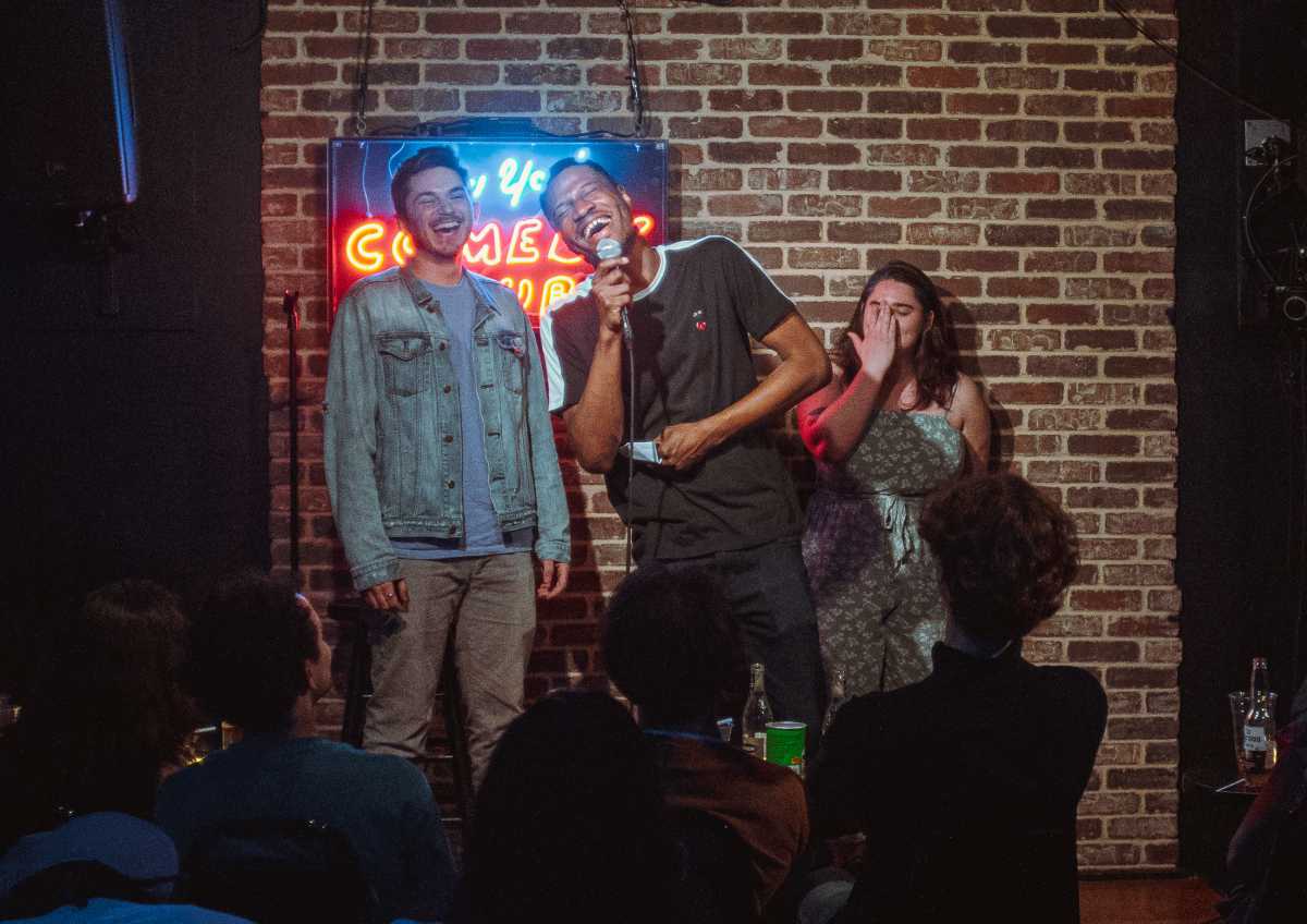 people on stage in dimly lit comedy club engaging in act