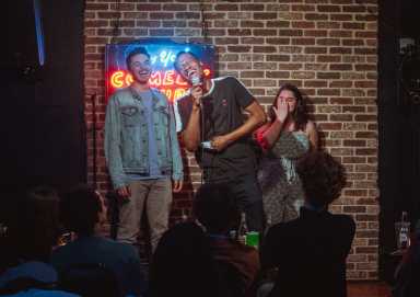 people on stage in dimly lit comedy club engaging in act