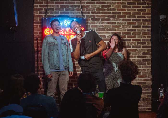 people on stage in dimly lit comedy club engaging in act